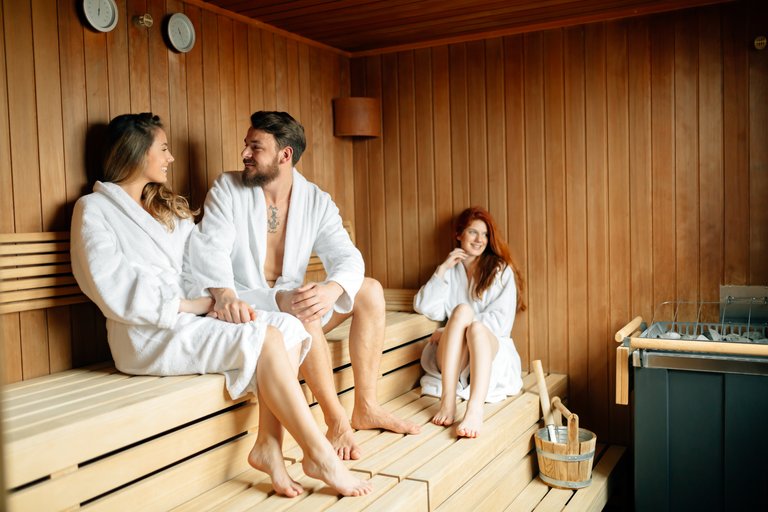 Gruppe junger Menschen sitzt mit Bademänteln in der Sauna